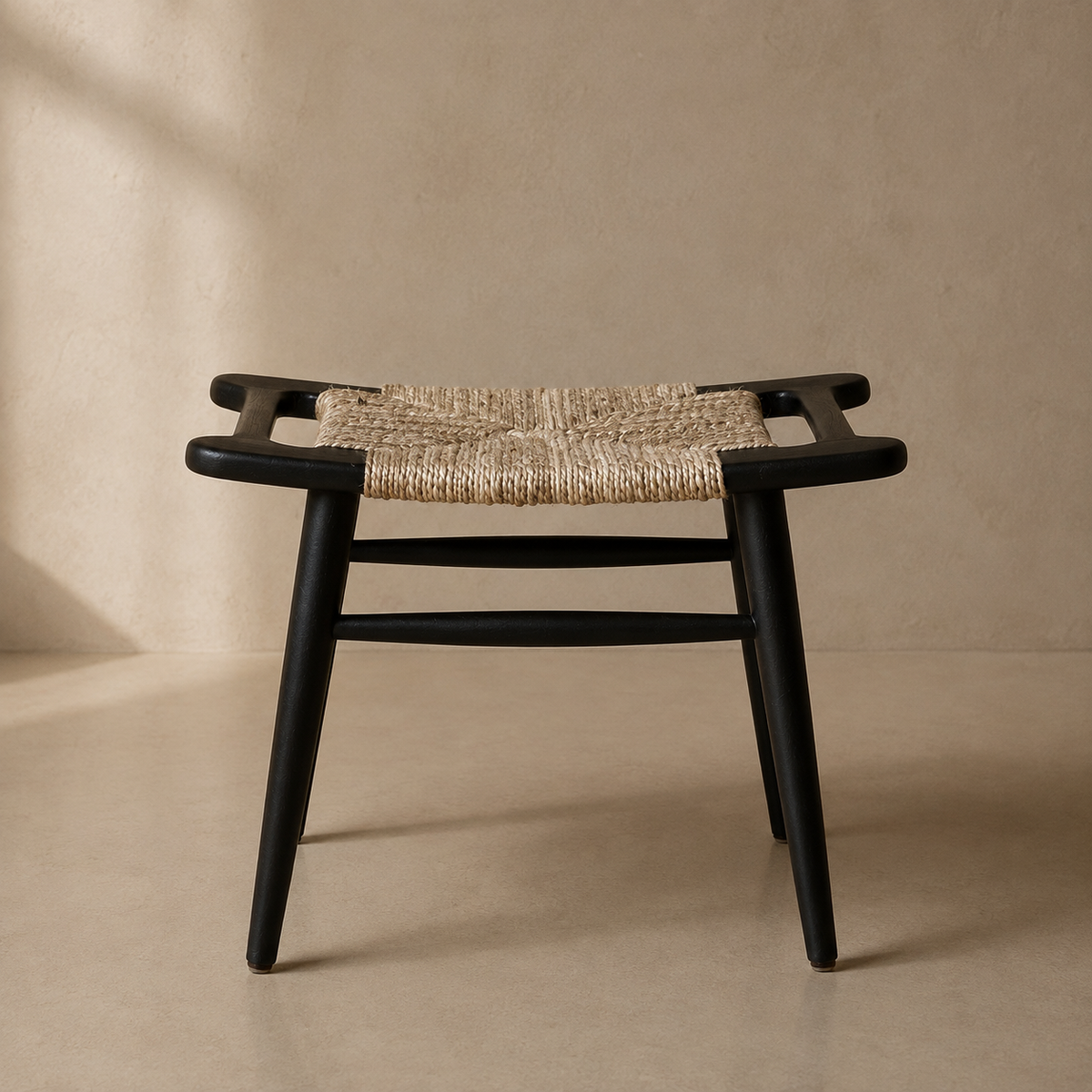 Pablo Hocker mit schwarzem Holzgestell und naturfarbener Flechtsitzfläche in einem warmen, minimalistischen Contemporary Interior.
