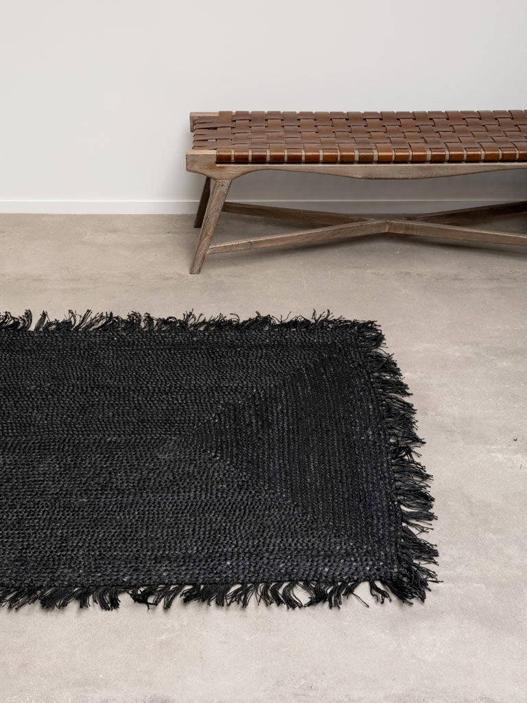 Noah Teppich, 120x180 cm, in Schwarz, im Flur platziert. Der Teppich aus Hanf bringt natürliche Wärme und eine entspannte Atmosphäre in den Raum. Mit seinem fransigen Look fügt er sich harmonisch in verschiedene Einrichtungsstile ein und sorgt für einen einladenden Eingangsbereich.