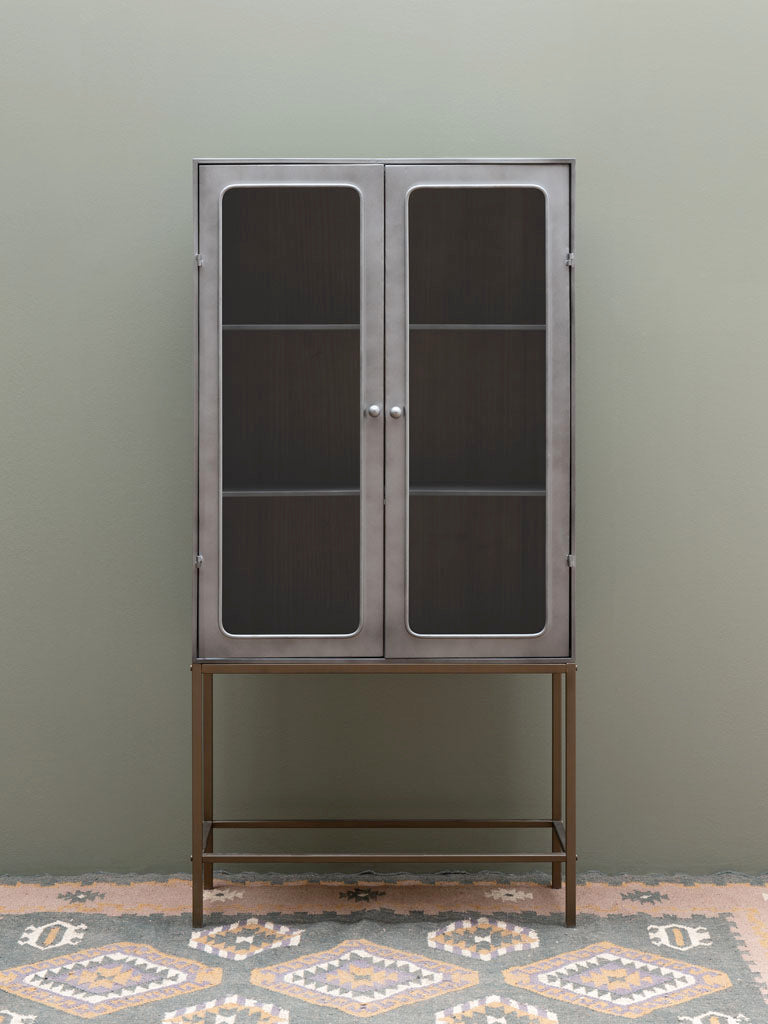 Boris Schrank aus Eisen und Messing, platziert im Wohnzimmer und dekoriert mit Körben und stilvollen Accessoires. Der graue und gunmetal Schrank verleiht deinem Raum Eleganz und schafft eine größere Raumwirkung.